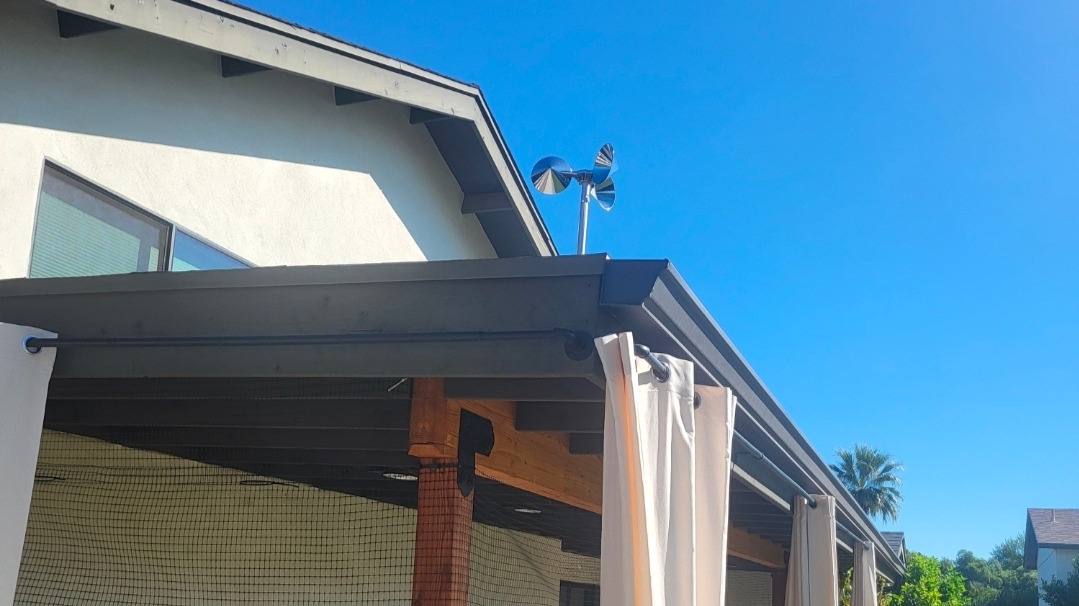 Bird deterrent spinner on roofline with mesh netting below protecting small dog patio from birds of prey in Phoenix AZ